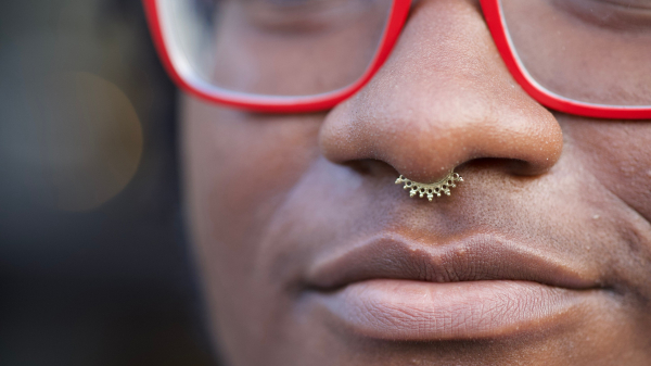 close up of septum piercing on black person wearing red glasses