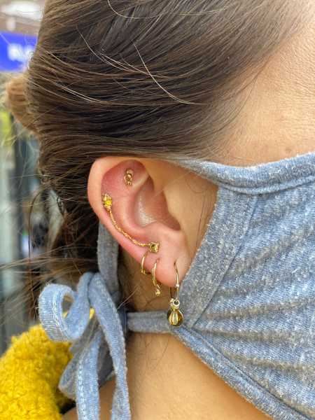 close up of several ear piercings with gold jewelry